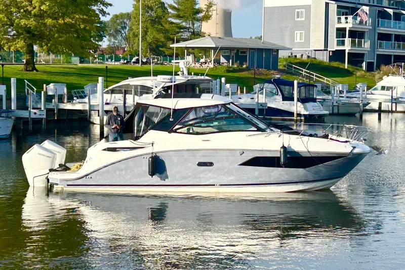 Slide: The Image of 2025 Sea Ray Sundancer 320 Outboard docked at a marina, surrounded by other boats. - 2