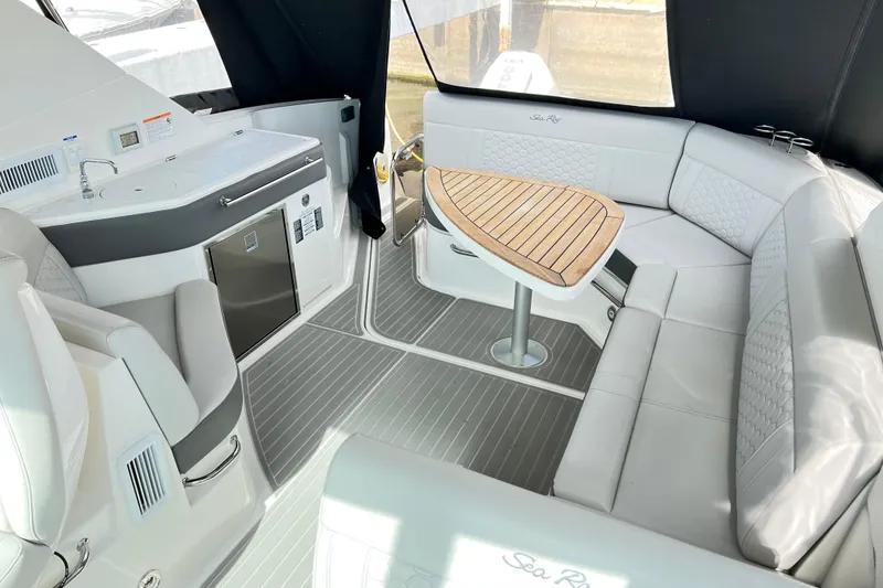 Slide: The Image of 2025 Sea Ray Sundancer 320 Outboard interior with seating, kitchenette, and wooden table. - 9