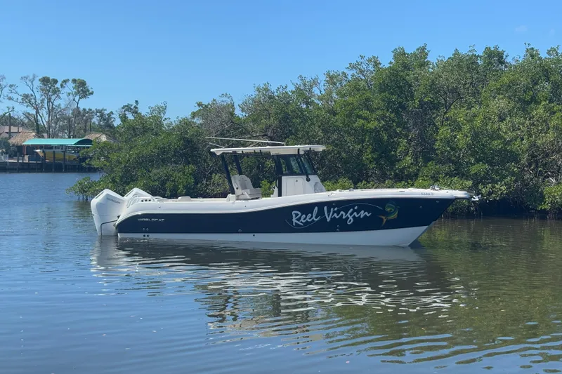 The Image of 2024 World Cat 325 CC boat on calm water near lush greenery. - 0