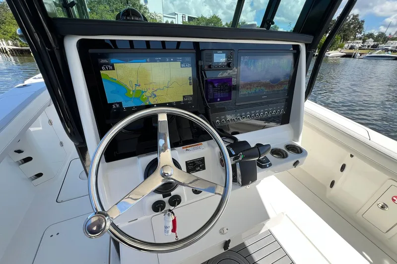 Slide: The Image of 2024 World Cat 325 CC boat helm with navigation screens and steering wheel. - 12