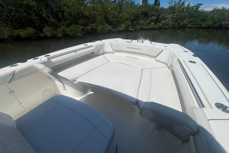 Slide: The Image of 2024 World Cat 325 CC boat interior with white seating, near lush greenery. - 18