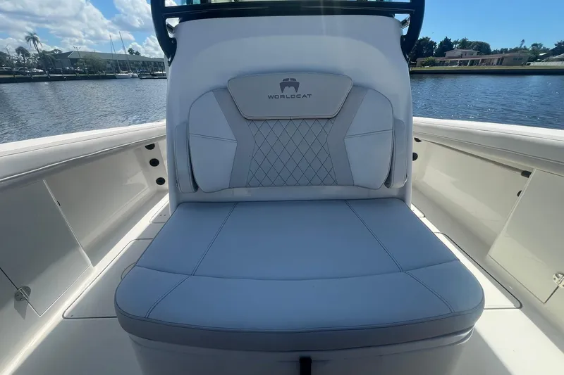 Slide: The Image of 2024 World Cat 325 CC boat interior with cushioned seating, docked by the water. - 20