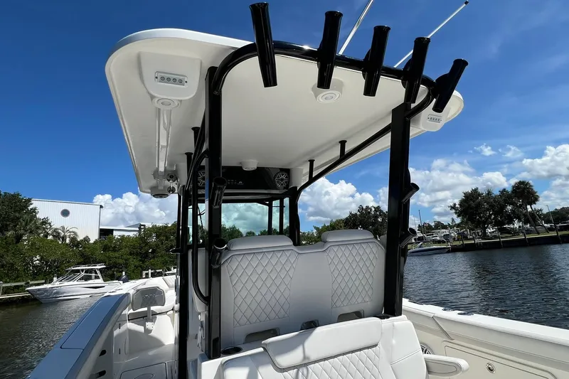 Slide: The Image of 2024 World Cat 325 CC boat interior with rod holders, white seating, and sunny waterfront view. - 21