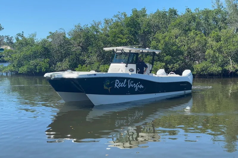 Slide: The Image of 2024 World Cat 325 CC boat navigating a calm river, surrounded by lush greenery. - 3