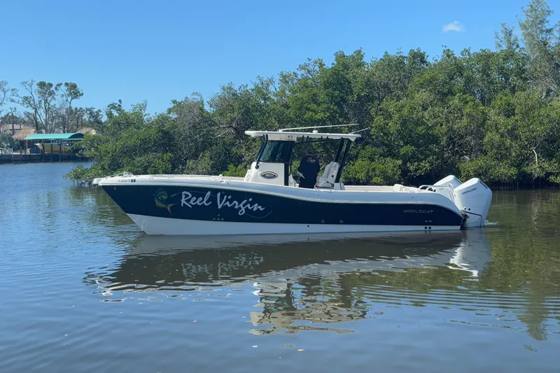 Slide: The Image of 2024 World Cat 325 CC boat on calm water, surrounded by lush greenery. - 4