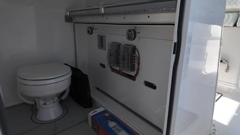 Slide: The Image of Interior of 2026 Twin Vee 280 GFX2 CC boat featuring a compact marine toilet. - 24