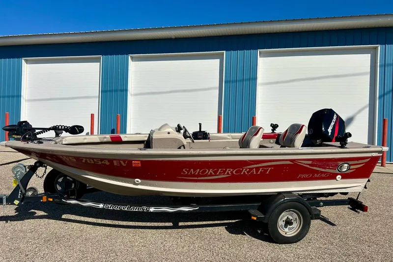 Slide: The Image of 2000 SMOKERCRAFT 161 Pro Mag boat on trailer, parked outside blue building. - 13