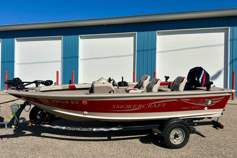 Slide: The Image of 2000 SMOKERCRAFT 161 Pro Mag boat on trailer, parked outside blue building. - 46