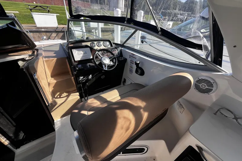 Slide: The Image of 2016 Sea Ray 280 Sundancer cockpit with steering wheel, Garmin display, and beige seating. - 10