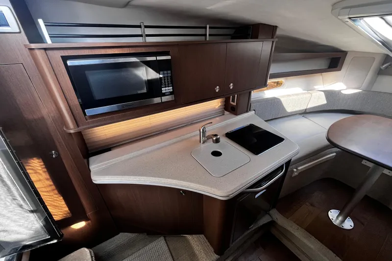 Slide: The Image of 2016 Sea Ray 280 Sundancer interior with kitchenette, microwave, and seating area. - 19