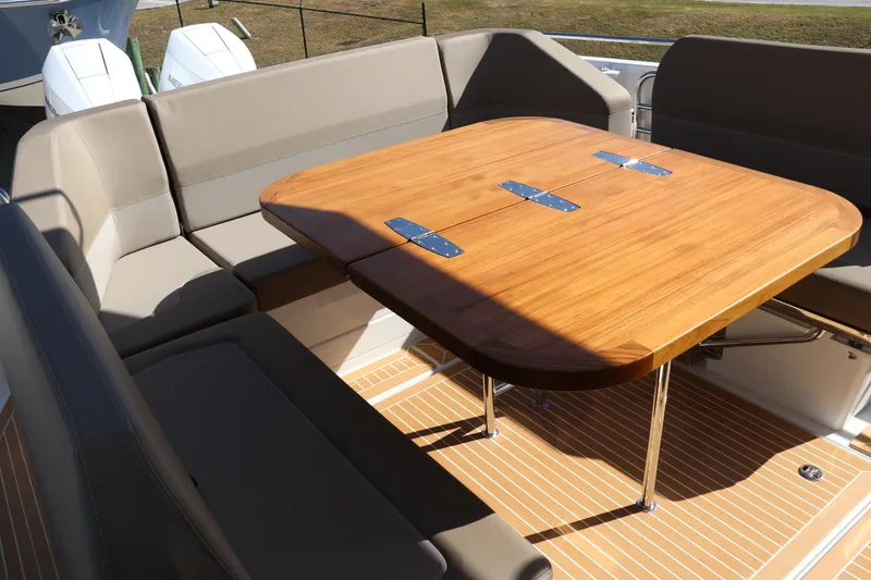 Slide: The Image of Luxurious seating area on 2025 Nimbus T11 boat with wooden table and cushioned benches. - 16