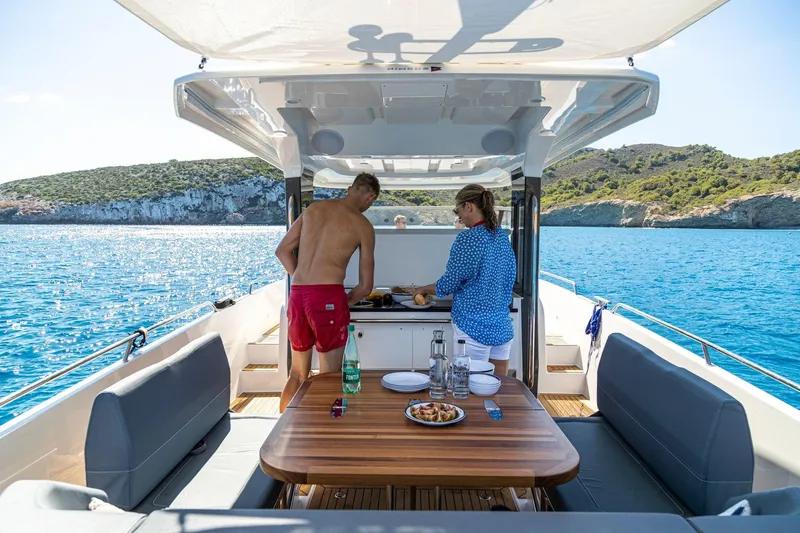 Slide: The Image of Couple enjoying a meal on a 2025 Nimbus T11 yacht, surrounded by scenic ocean views. - 26