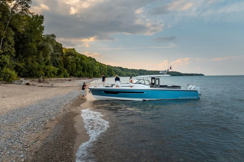 Slide: The Image of 2025 Nimbus T11 boat docked on a scenic beach with people enjoying the view. - 3