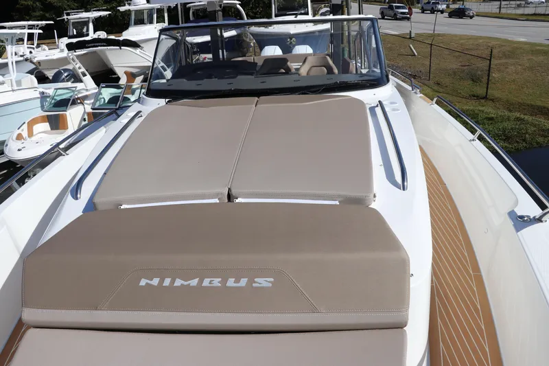 Slide: The Image of 2025 Nimbus T11 boat with beige sunbed, docked among other vessels. - 59