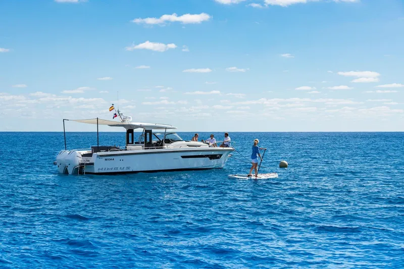 Slide: The Image of Nimbus T11 2025 boat with people enjoying paddleboarding on a sunny ocean day. - 6