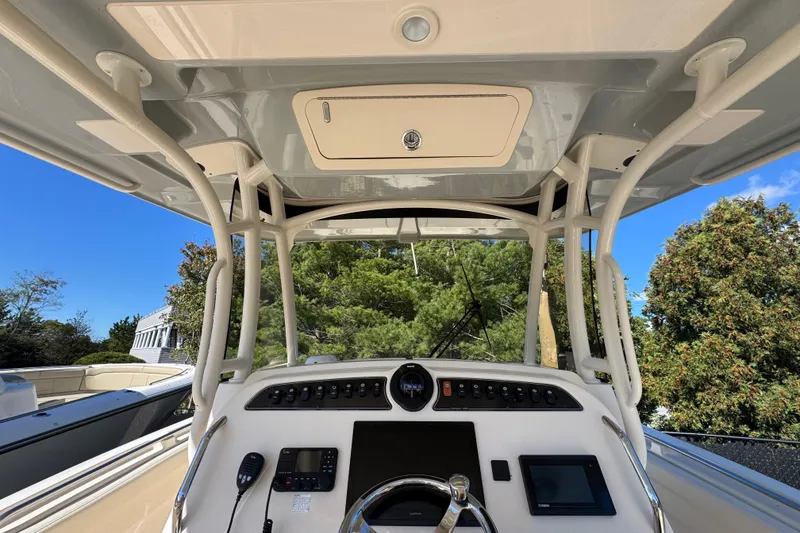 Slide: The Image of 2022 Grady-White Canyon 326 boat helm with controls and steering wheel, under clear blue sky. - 21