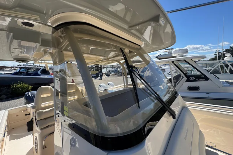 Slide: The Image of 2022 Grady-White Canyon 326 boat interior with seating and windshield, docked under clear skies. - 44