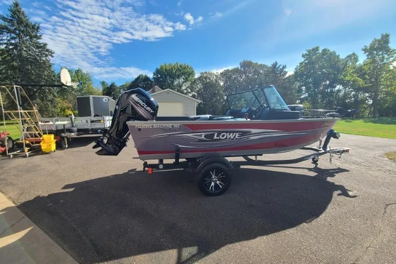 Slide: The Image of 2016 Lowe Fishing Machine 165SC Pro boat on trailer in sunny driveway. - 2