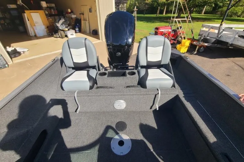 Slide: The Image of 2016 Lowe Fishing Machine 165SC Pro interior with two seats and motor in a garage setting. - 8
