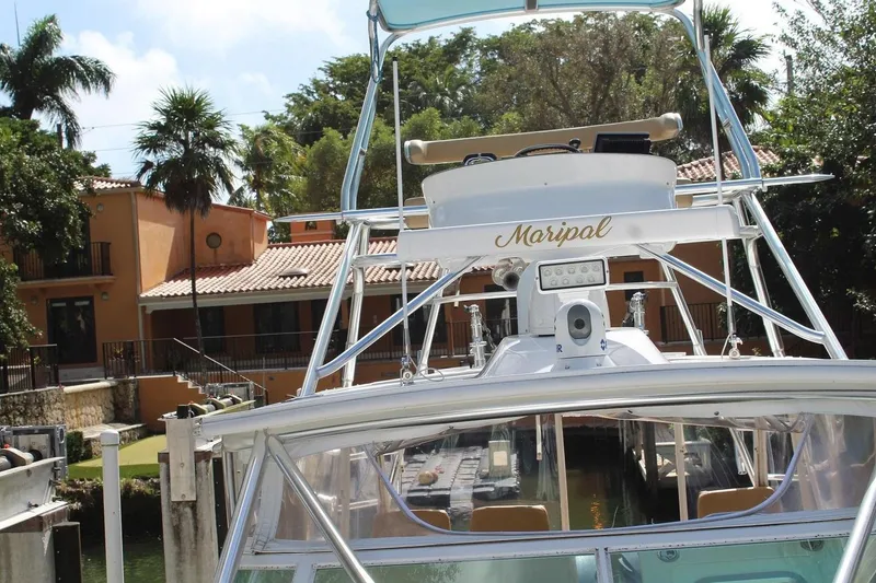 Slide: The Image of 2008 Contender 38 Express boat docked near a tropical house with palm trees. - 2