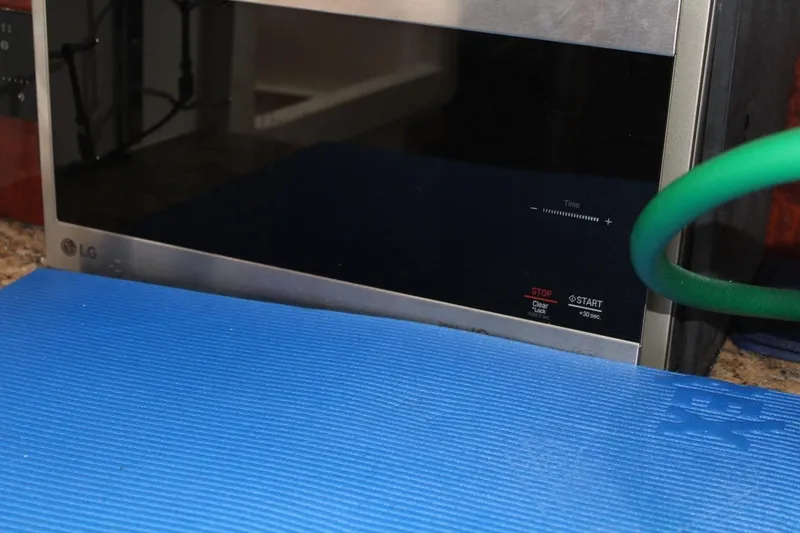 Slide: The Image of A microwave oven on a countertop with a blue mat and green hose. - 44