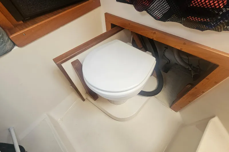 Slide: The Image of 2006 Carolina Classic 25 Express boat interior with compact marine toilet setup. - 17