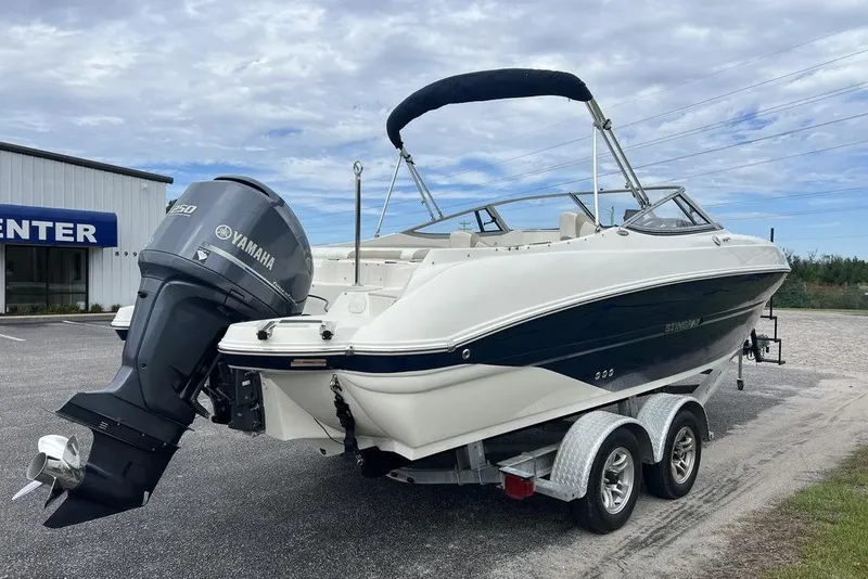 Slide: The Image of 2015 Stingray 234LR boat with Yamaha outboard motor on a trailer, parked outdoors. - 1