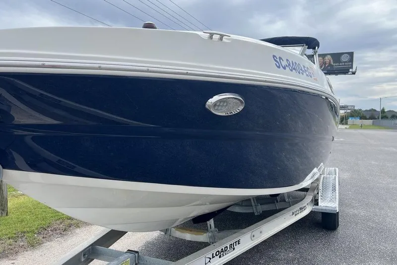 Slide: The Image of 2015 Stingray 234LR boat on trailer, blue and white hull, parked outdoors. - 14