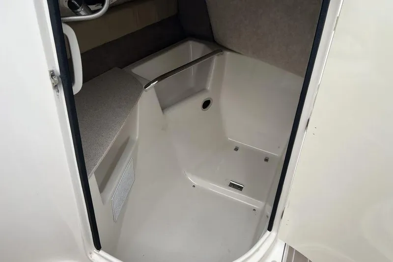 Slide: The Image of 2015 Stingray 234LR boat interior, featuring a compact cabin space with seating and storage. - 29
