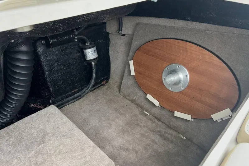 Slide: The Image of 2015 Stingray 234LR boat interior storage compartment with wooden cover and ventilation hose. - 32