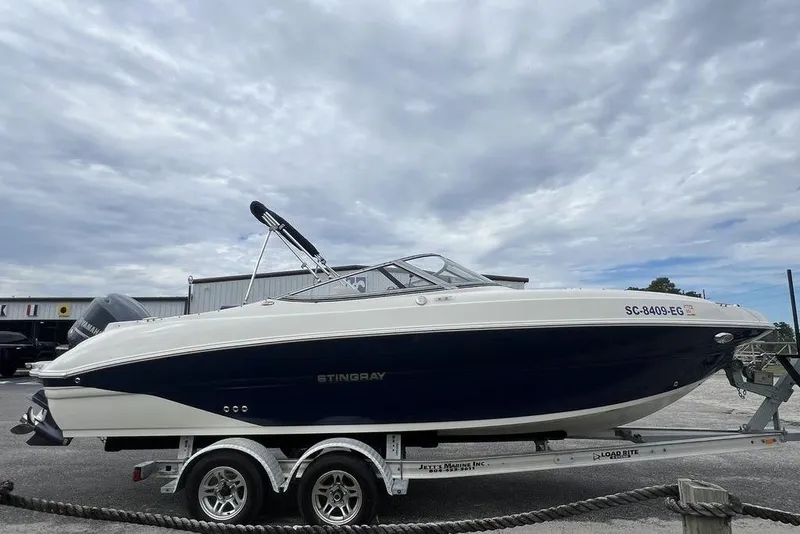 Slide: The Image of 2015 Stingray 234LR boat on trailer under cloudy sky. - 36