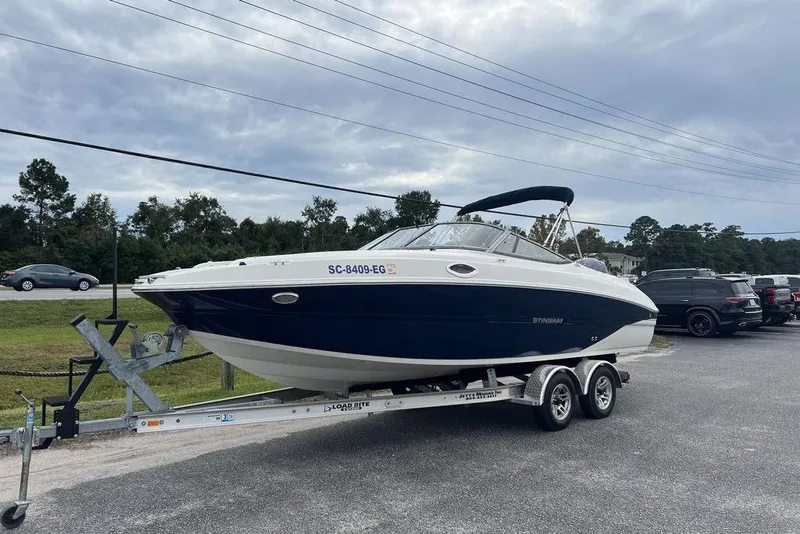 Slide: The Image of 2015 Stingray 234LR boat on trailer, parked outdoors under cloudy sky. - 4