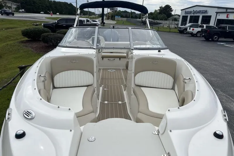 Slide: The Image of 2015 Stingray 234LR boat with white seating and wood accents, parked near showroom. - 9