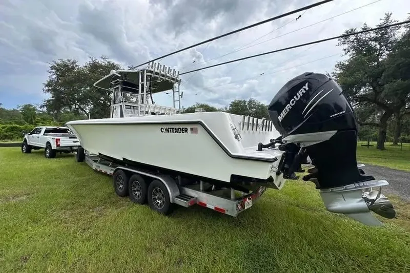 Slide: The Image of 2019 Contender 39 ST boat on trailer, with Mercury outboard engine, parked on grass. - 5