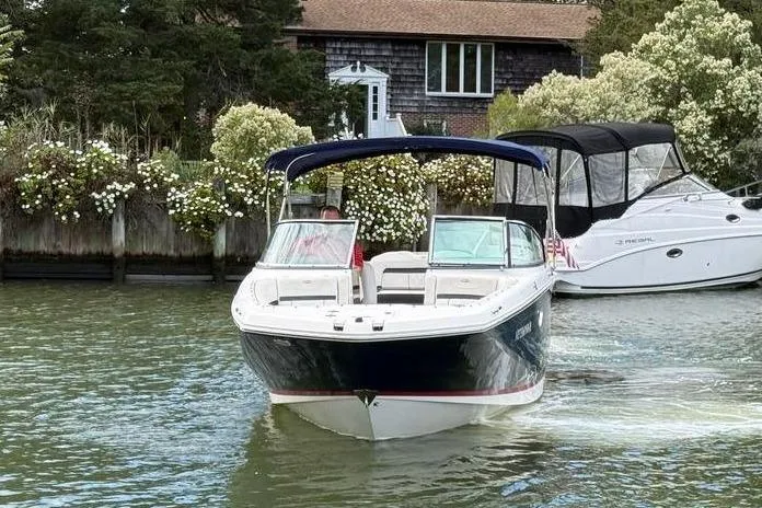 Slide: The Image of 2017 Regal 26 OBX boat cruising on a scenic waterway near a house. - 8