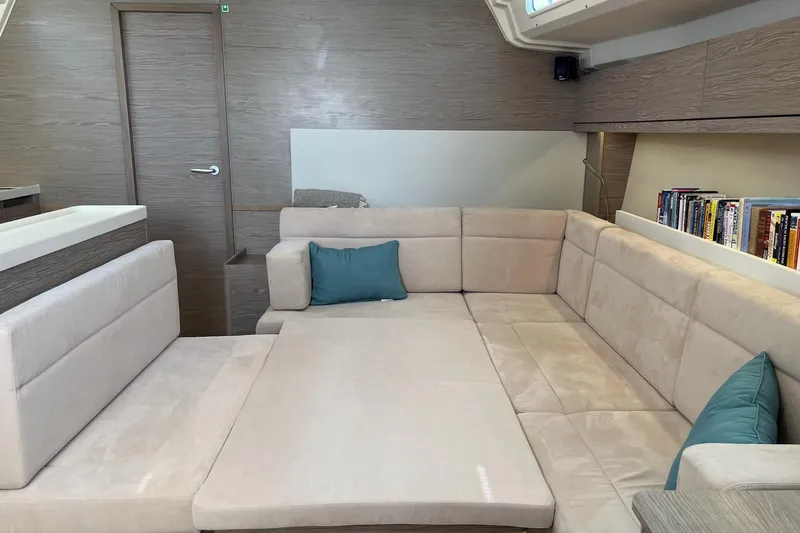 Slide: The Image of Luxurious interior of 2021 Hanse 508 yacht with beige seating and bookshelf. - 21