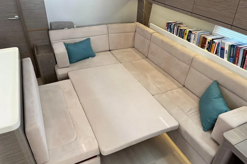 Slide: The Image of Luxurious interior of 2021 Hanse 508 yacht with beige seating and bookshelf. - 22