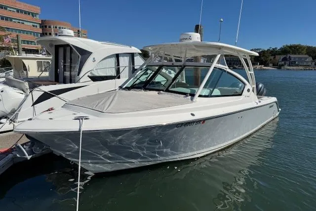 Slide: The Image of 2021 Pursuit DC 266 Dual Console boat docked in marina, clear sky background. - 1