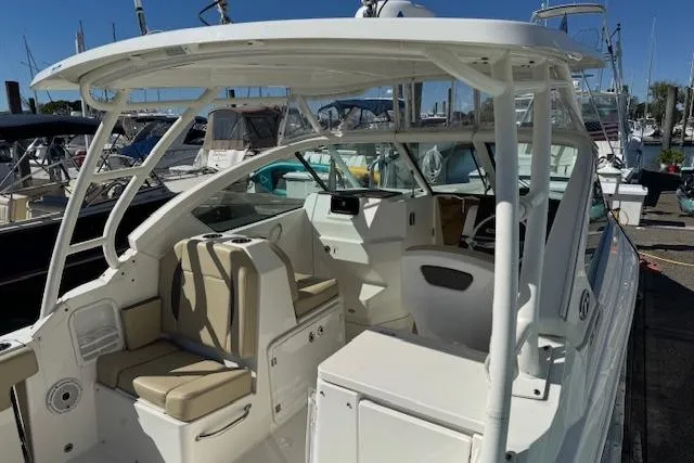 Slide: The Image of 2021 Pursuit DC 266 Dual Console boat with beige seating at a marina. - 4