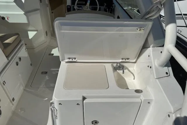 Slide: The Image of 2021 Pursuit DC 266 Dual Console boat interior with sink and storage compartments. - 8