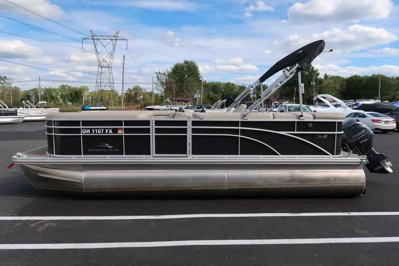 Slide: The Image of 2020 Bennington 21 SL pontoon boat parked in a lot under a blue sky. - 5
