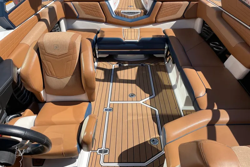 Slide: The Image of 2021 Nautique Super Air Nautique G23 interior with tan leather seats and wood-style flooring. - 12