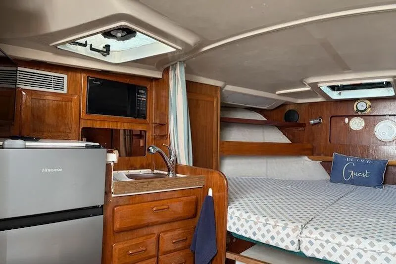 Slide: The Image of 1995 Luhrs Open Express cabin interior with kitchenette, bed, and nautical decor. - 12