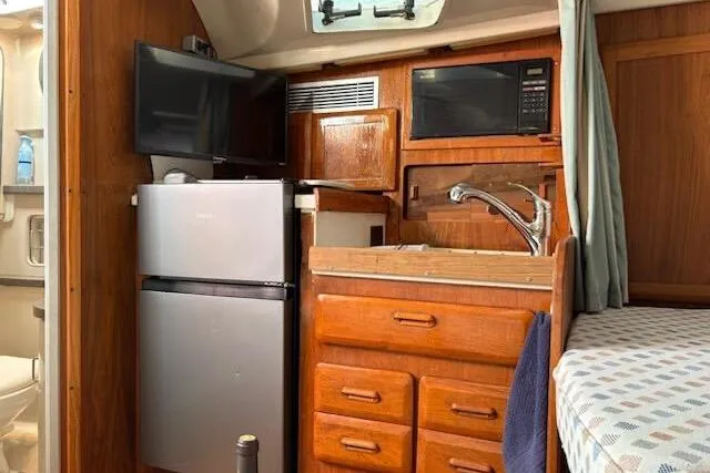 Slide: The Image of 1995 Luhrs Open Express interior with kitchenette, featuring fridge, microwave, and wooden cabinetry. - 15