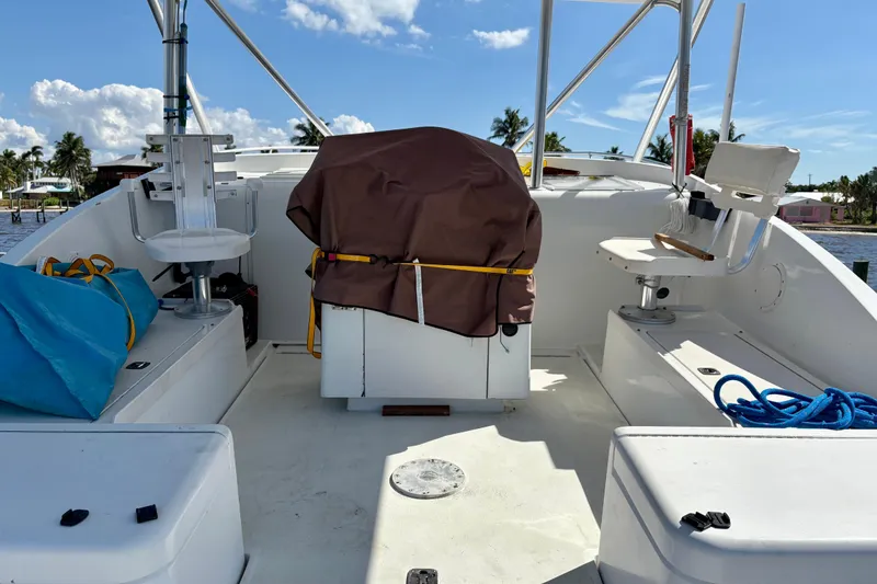 Slide: The Image of 1995 Luhrs Open Express boat deck with seating, covered equipment, and blue rope under a sunny sky. - 22