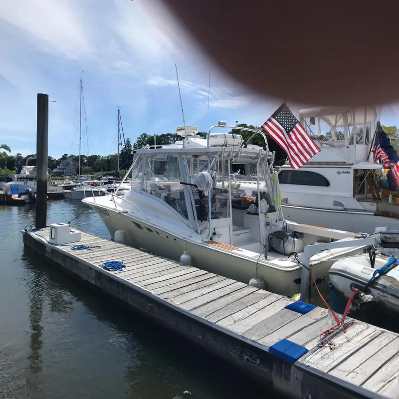 The Image of 1995 Luhrs Open Express boat docked with American flag, clear skies, and marina background. - 0