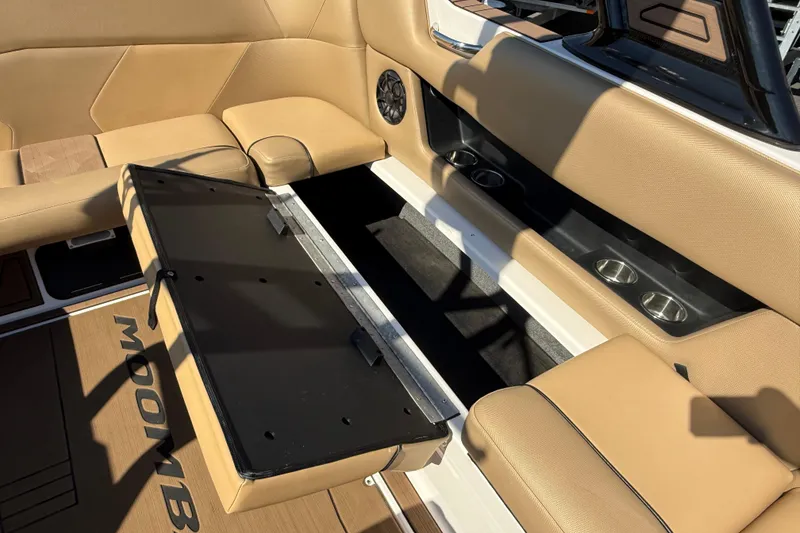 Slide: The Image of 2021 Moomba Max boat interior with tan seating and open storage compartment. - 13