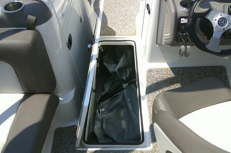 Slide: The Image of 2010 Yamaha Boats 242 Limited S interior with open storage compartment and steering wheel. - 16