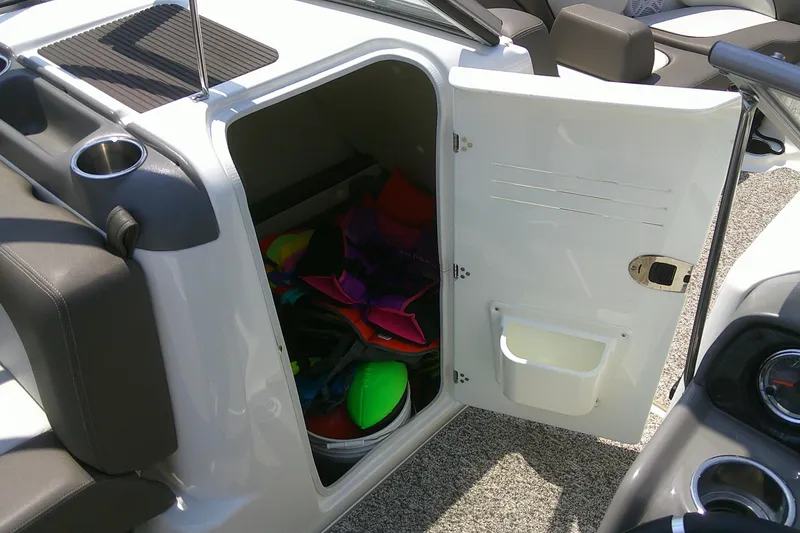 Slide: The Image of Open storage compartment on 2010 Yamaha Boats 242 Limited S, containing colorful life jackets. - 17