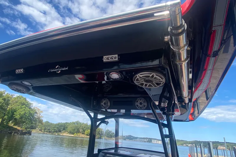 Slide: The Image of 2021 Fountain 34 SC boat with sleek black canopy and speakers, docked by a scenic lake. - 30